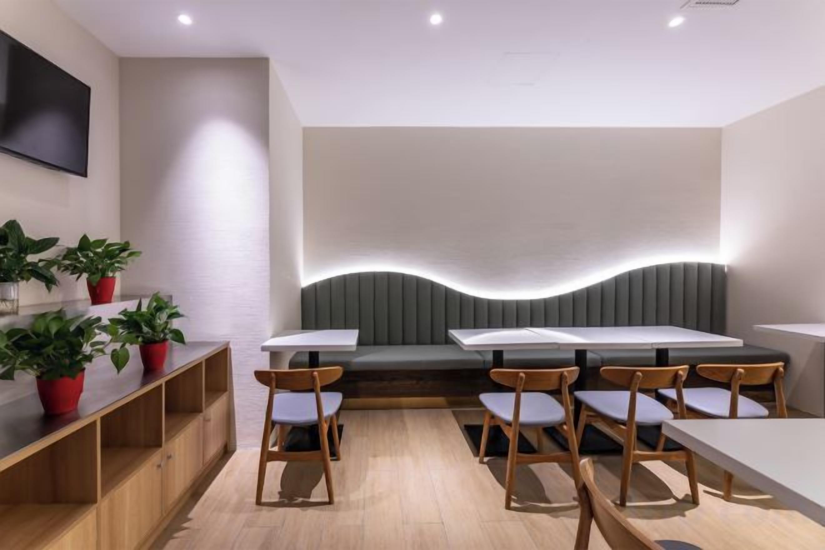 Un comedor moderno con una mesa larga, asientos acolchados y plantas en macetas.