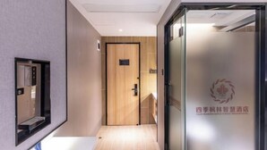 Un pasillo de hotel con una puerta de madera, una zona de recepción con pared de vidrio y un letrero con caracteres chinos.