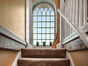 A staircase with a view of a large arched window and potted plants on the windowsill. - 2 bedroom accommodation in Appleby (Appleby)