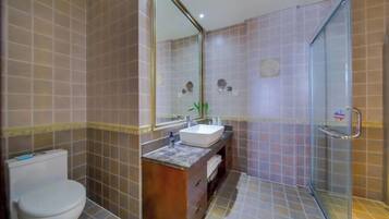 A bathroom with a toilet, a sink, a mirror, and a shower area.