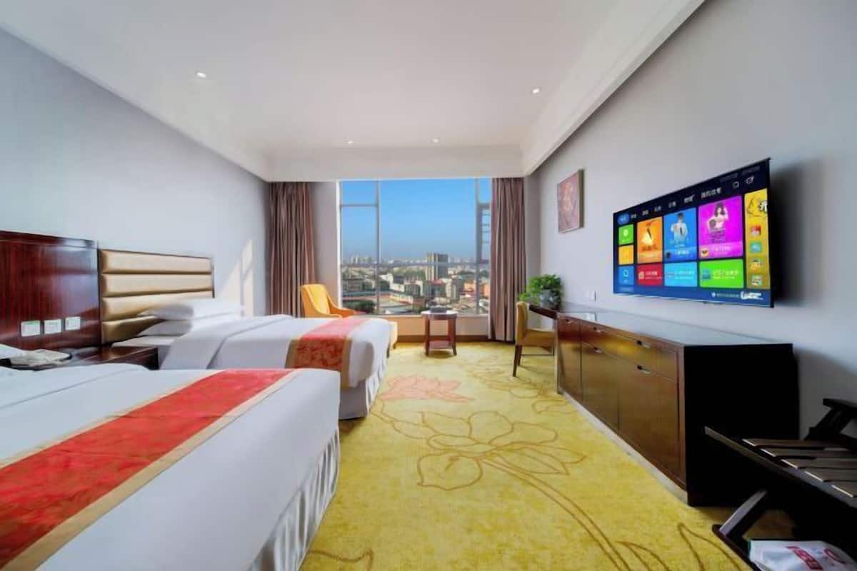 Camera d'albergo con due letti, televisione, scrivania e vista sulla città.