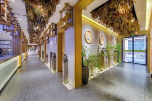 Un vestíbulo de hotel con un largo pasillo, techo decorativo y una recepción.