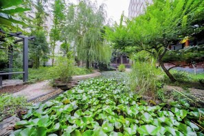 A garden with various plants and trees, a pathway, and a structure on the left. - Pingyu Hotel (Pingyu)
