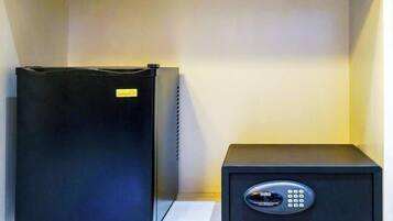 A black safe and a black refrigerator on a white shelf.