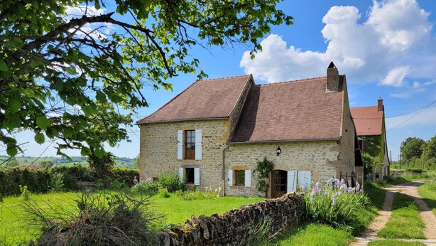 A stone house with a tiled roof, a stone wall in front, and a path leading to it. - Oyé's house (Oyé)