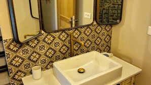 A bathroom with a white sink, two mirrors, and patterned tiles. - Oyé's house (Oyé)
