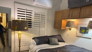 A bedroom with a bed, bedside lamp, wooden cabinet, and a framed picture on the wall. - Cozy 1-bedroom mobile home with AC, WiFi in tranquil Desert Hot Springs (Desert Hot Springs)