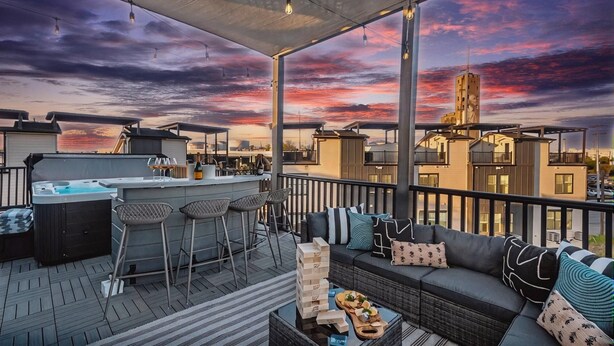 Une terrasse sur le toit avec un jacuzzi, un espace bar et des sièges.