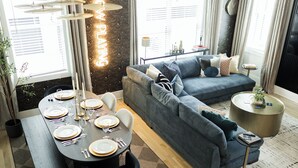 Un salon moderne avec un coin repas, comprenant un ensemble de canapés, une table basse ronde et une table à manger pour six personnes.