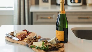 Un comptoir de cuisine avec une planche à découper pour charcuterie et une bouteille de champagne.