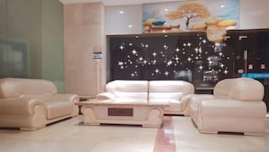 A lobby with a beige sofa set, a coffee table, and a large window with a view of the city. - Vienna Hotel （Dongguan Changping South Station Baihua Times Square Hotel） (Dongguan)