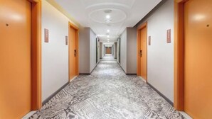 A hotel hallway with patterned flooring, wooden doors, and a ceiling with recessed lighting. - Vienna Hotel （Dongguan Changping South Station Baihua Times Square Hotel） (Dongguan)