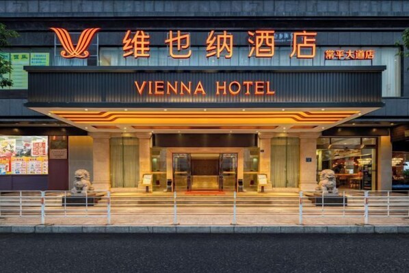 The Vienna Hotel entrance with a modern facade, illuminated signage, and two lion statues at the entrance. - Vienna Hotel (Dongguan Changping South Station Baihua Times Square Hotel) (Dongguan)