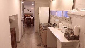 Una cocina compacta equipada con refrigerador, cafetera, tostadora y lavaplatos.