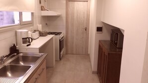 Una cocina compacta con pileta, estufa y microondas.