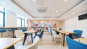 A modern dining area with tables and chairs, a colorful mural on the back wall, and large windows on the left.