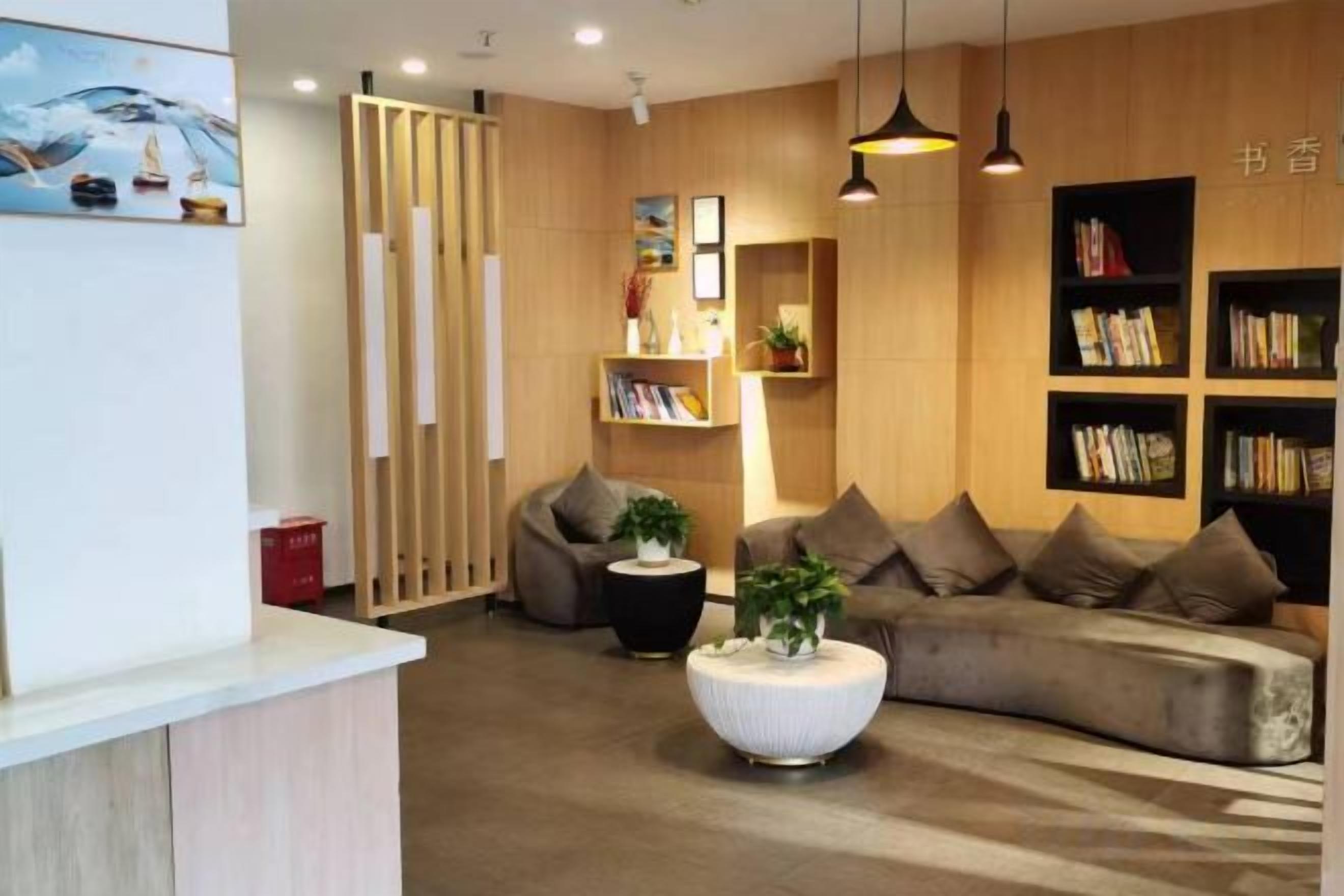Een moderne receptie met een balie, een zithoek met banken en boekenkasten.