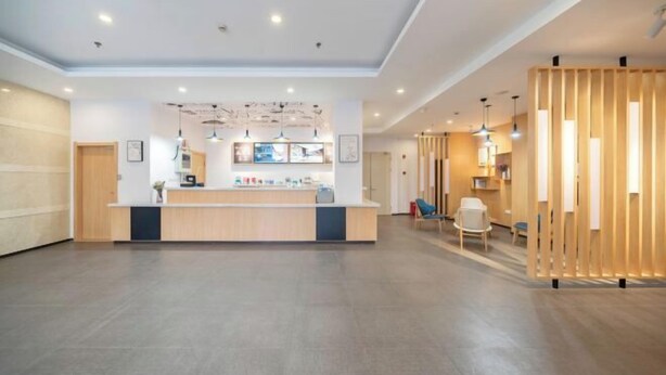 A spacious lobby with a reception desk, wooden partitions, and modern lighting fixtures.