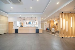 Un hall amplio con mostrador de recepción, separadores de madera e iluminación moderna.