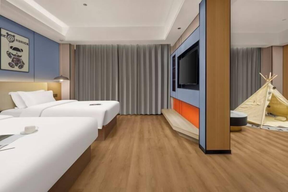 Une chambre d’hôtel avec deux lits, une télévision, une tente et une étagère fixée au mur.