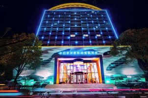 A hotel with a modern facade, illuminated entrance, and a prominent sign.