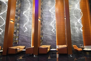 A modern lobby with high wooden columns, a marble wall, and a seating area with sofas and armchairs. - Siji Ruchun Hotel (Changsha County)
