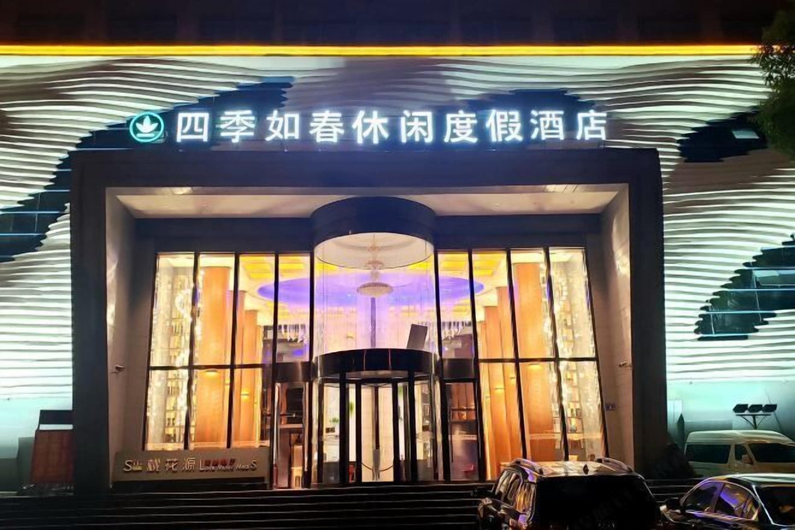 A hotel entrance with a modern design, featuring a large glass facade and a revolving door.