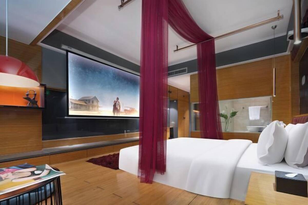 Une chambre d’hôtel moderne dotée d’un grand lit, d’une télévision et offrant une vue sur le paysage urbain.