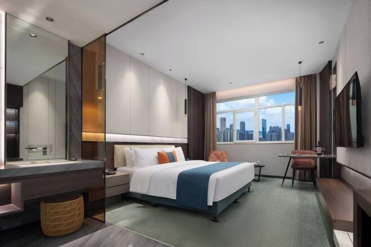 Une chambre d’hôtel moderne dotée d’un grand lit, d’un bureau, d’une chaise et offrant une vue sur le panorama urbain.