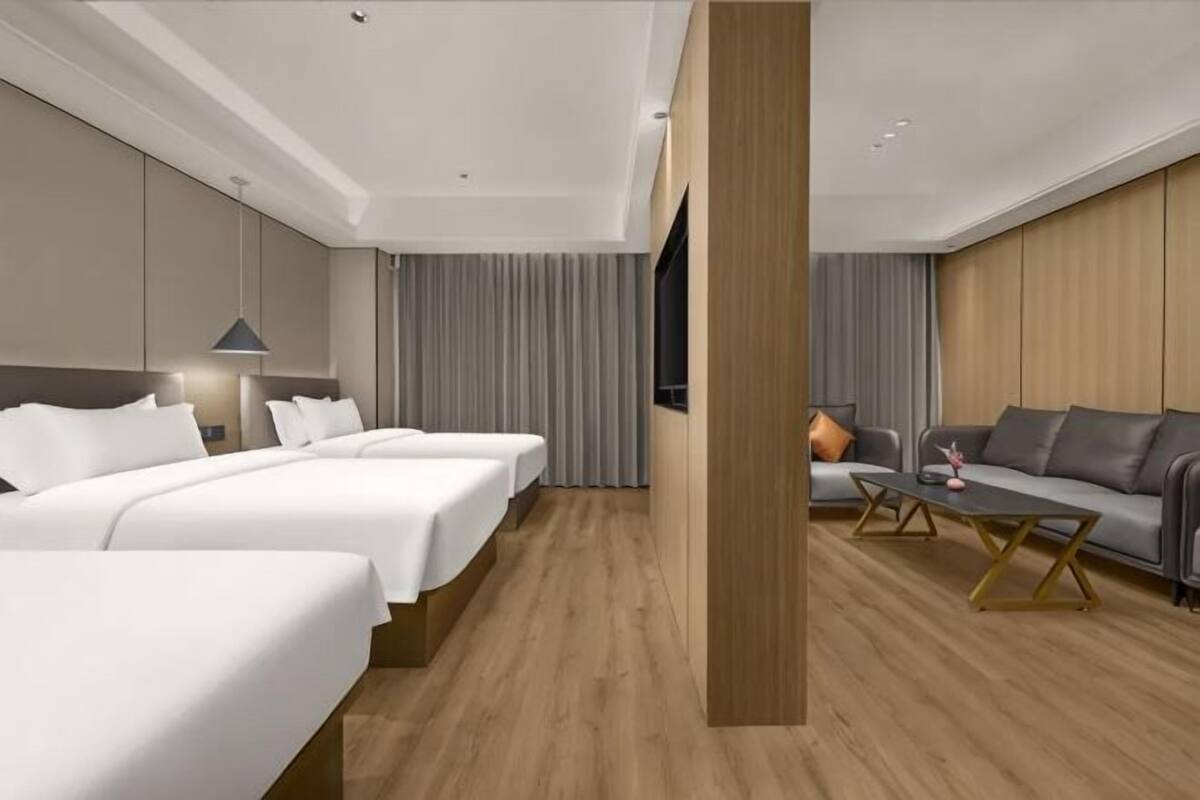 Une chambre d’hôtel avec deux lits, un canapé, une télévision et un plancher en bois.