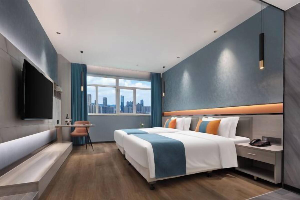 Une chambre d’hôtel moderne dotée d’un grand lit, d’un bureau, d’une chaise, d’une télévision et offrant une vue sur la ville.
