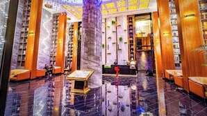 Un vestíbul ampli amb un paviment brillant, una recepció central i prestatges de llibres a banda i banda.