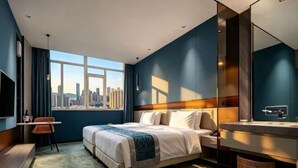 Habitació d'hotel moderna amb vista a la ciutat, un llit, una taula de treball i un mirall gran.