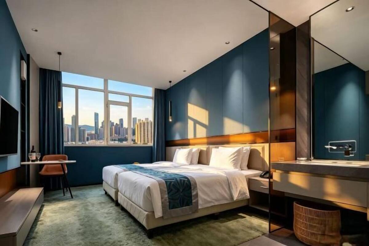 Une chambre d’hôtel moderne avec vue sur la ville, un lit, un bureau et un grand miroir.
