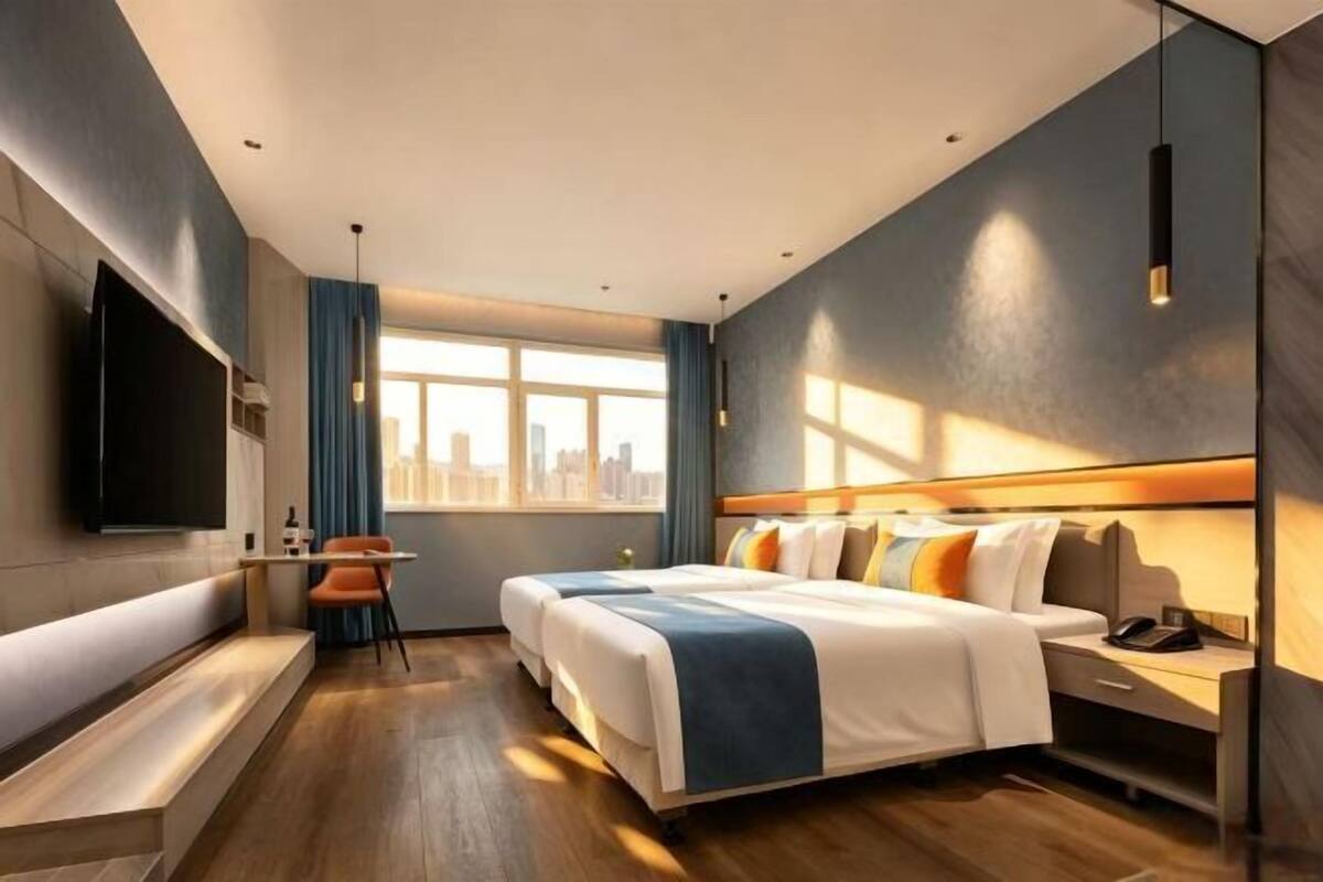 Une chambre d’hôtel moderne dotée d’un grand lit, d’une télévision, d’un bureau et d’une fenêtre donnant sur la ville.