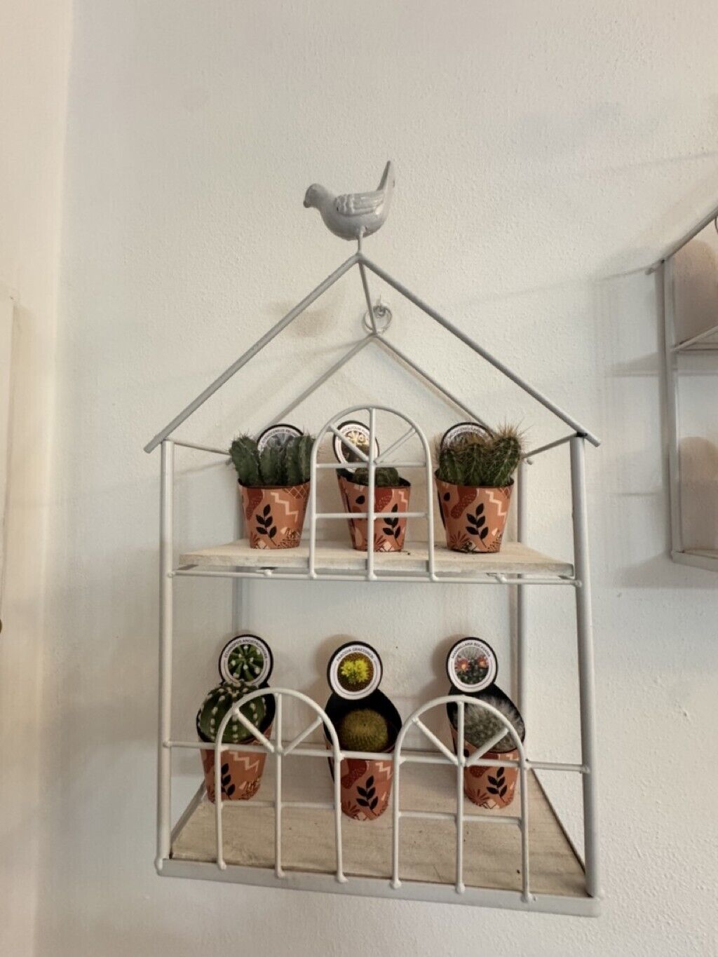 Une étagère en métal en forme de maison, sur laquelle sont disposées des plantes en pot.