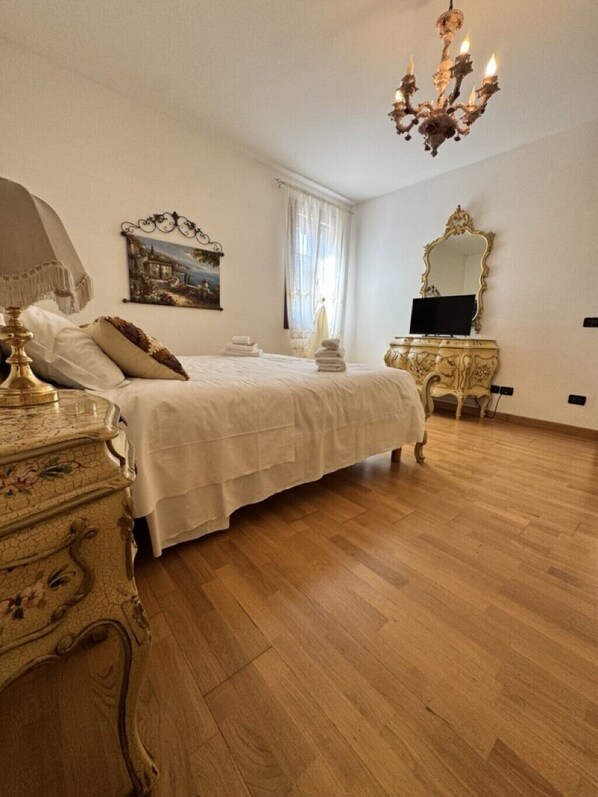 Une chambre à coucher avec un lit, une commode, un miroir et un lustre.