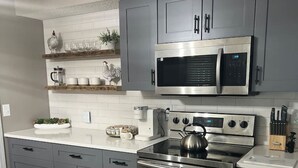 A modern kitchen with grey cabinets, a stainless steel stove, and a microwave.