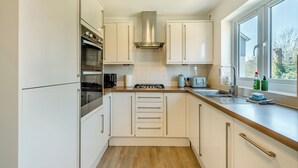 A modern kitchen with white cabinets, stainless steel appliances, and a window providing a view of the outdoors. - 3 bedroom accommodation in Paignton (Paignton)