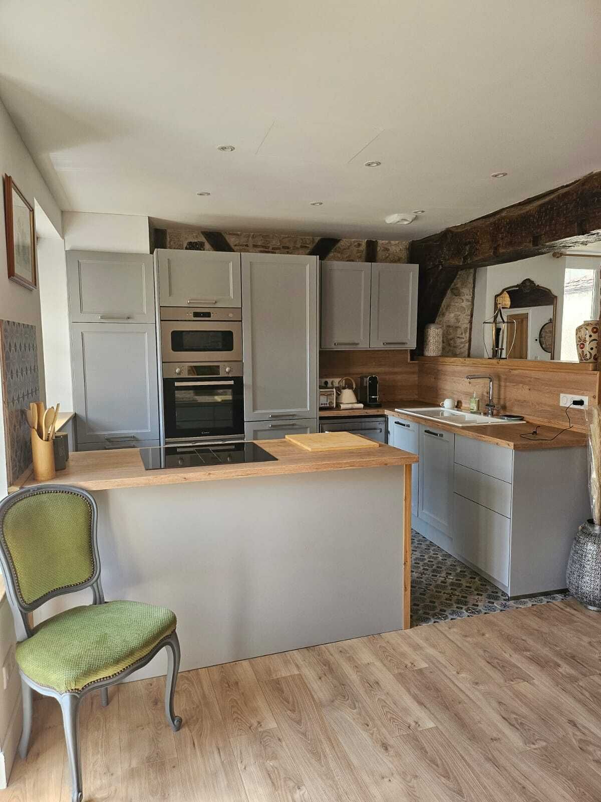 A modern kitchen with grey cabinets, a wooden island, and a built-in oven.