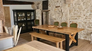 A rustic kitchen with a wooden table, benches, and a black countertop.