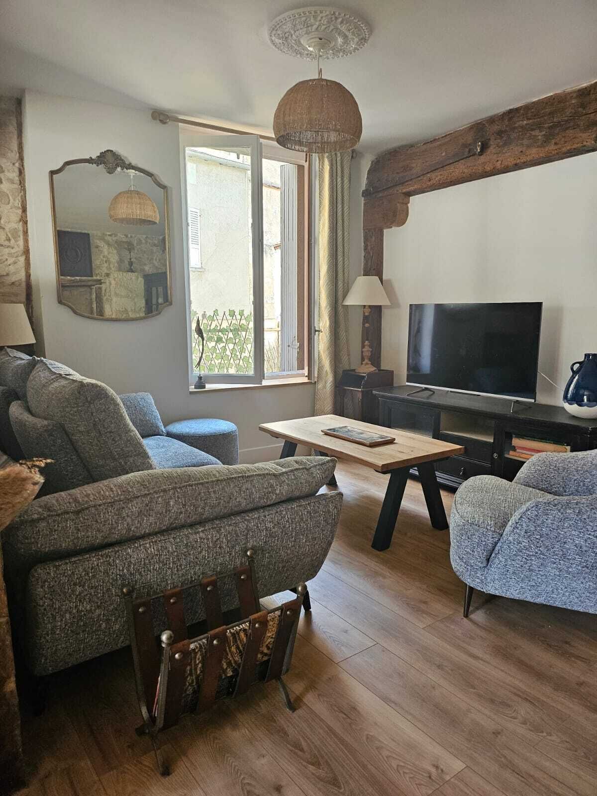 A cozy living room with a wooden floor, a sofa, a television, and a table.
