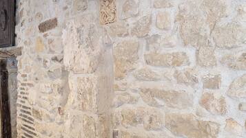 A stone wall with a decorative carving, a wooden beam ceiling, and a vent.