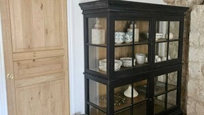 A wooden cabinet with glass doors containing kitchenware.