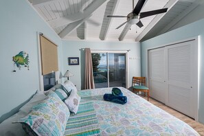 Ein Schlafzimmer mit Bett, Deckenventilator, Stuhl, einer Schiebetür und einem Kleiderschrank.