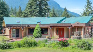 A lodge with a green roof, wooden exterior, and a mountain backdrop.