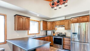 A modern kitchen with wooden cabinets, stainless steel appliances, and a large island.