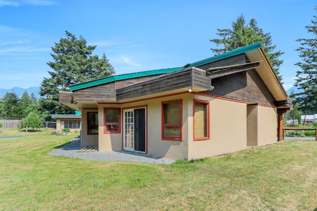 Una casa de un piso con techo inclinado, puerta principal y un pequeño porche.