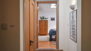 A hallway leading to a bedroom with a bed, a wooden wardrobe, and a wall-mounted light fixture. - 1 bedroom accommodation in East Cowton (East Cowton)