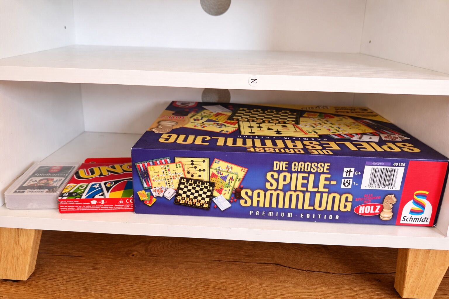 A shelf with a board game box labeled 'Die Grosse Spiele-Sammlung' and a smaller box labeled 'UNO'.